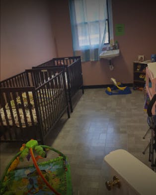 Two cribs in a room with a window and play mat
