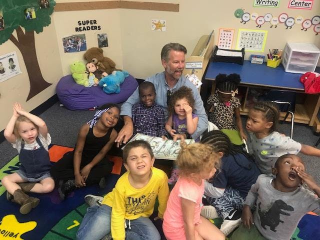 Adult and multiple children sitting on a classroom floor