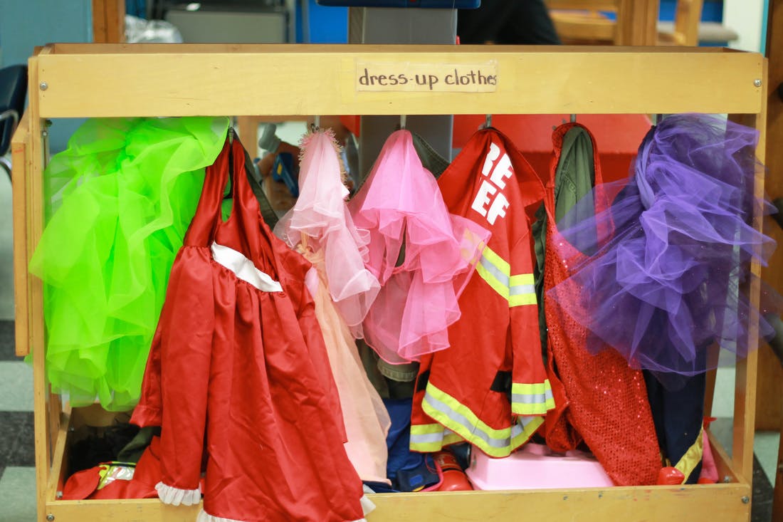 Dress-up clothes hanging on a rack with a sign that says "dress-up clothes"