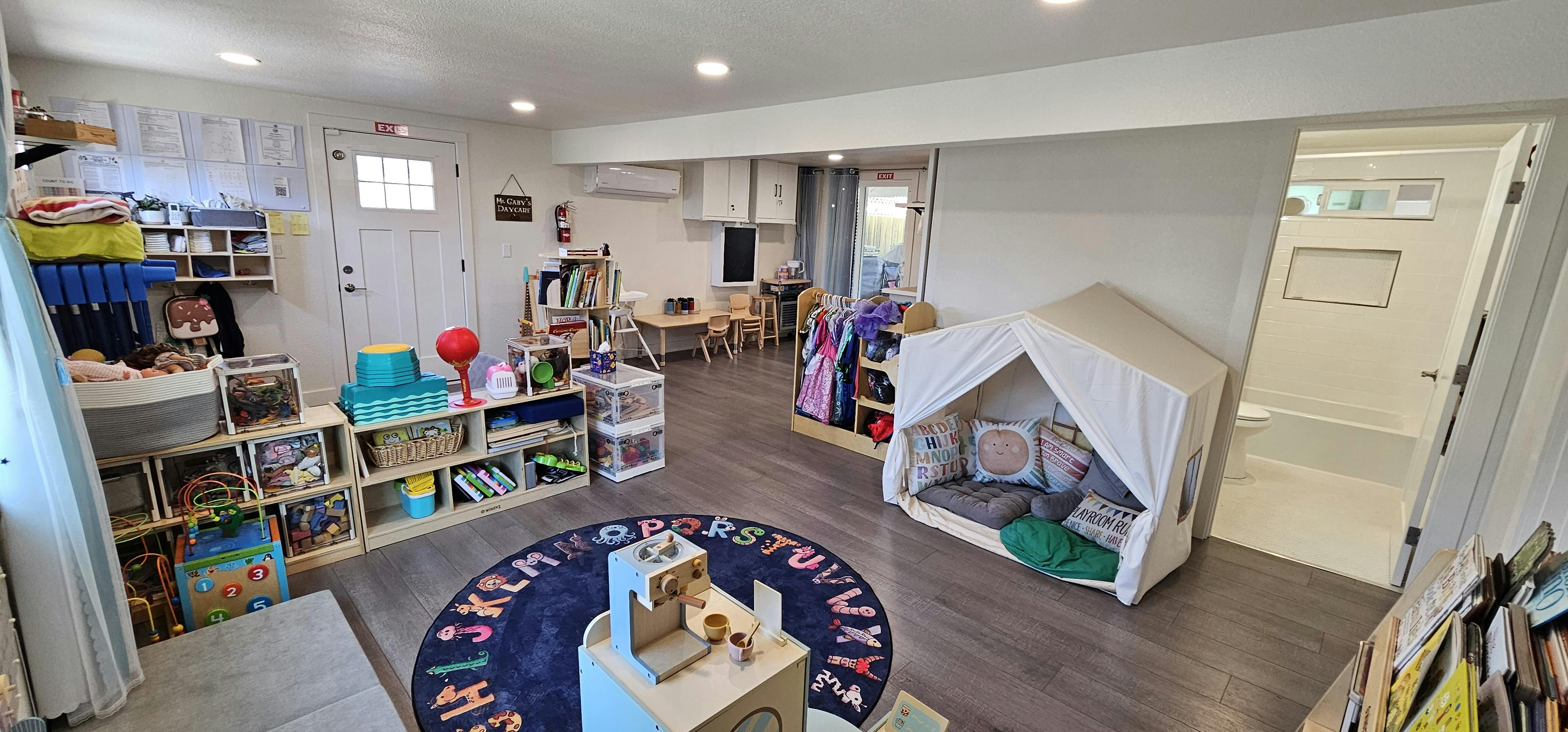 Playroom with toys, shelves, small tables, a dress-up rack, and a play tent