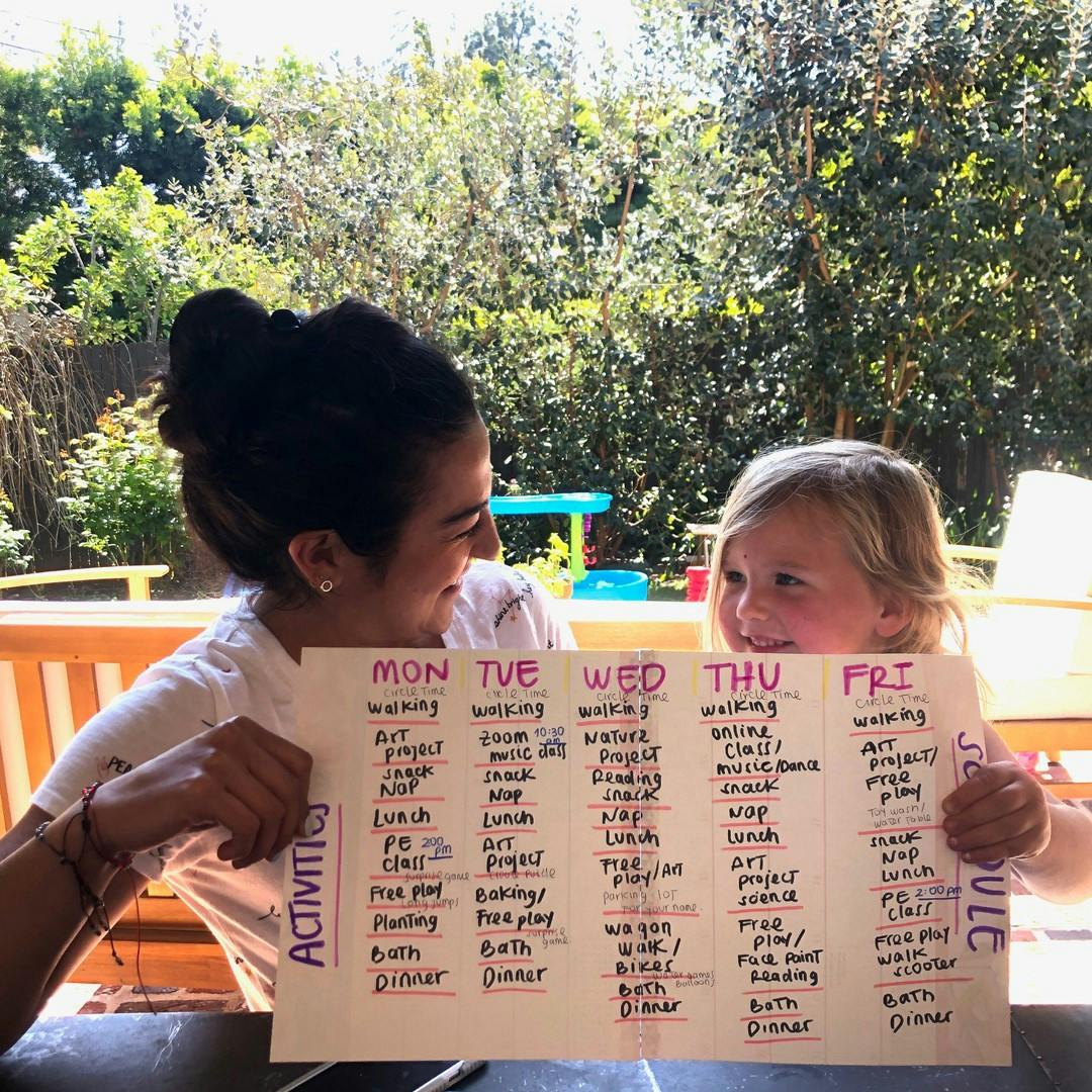 Person and child holding up a schedule with activities for the week