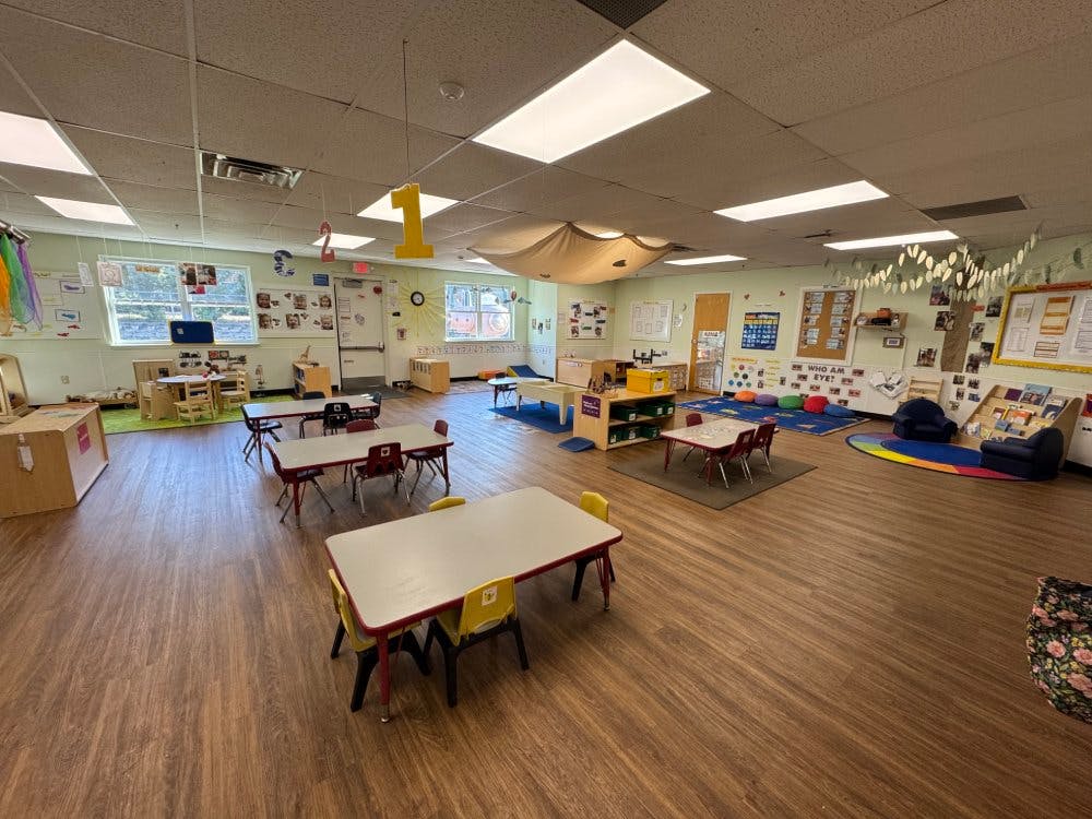 empty classroom with small tables and chairs, play areas, and decorations