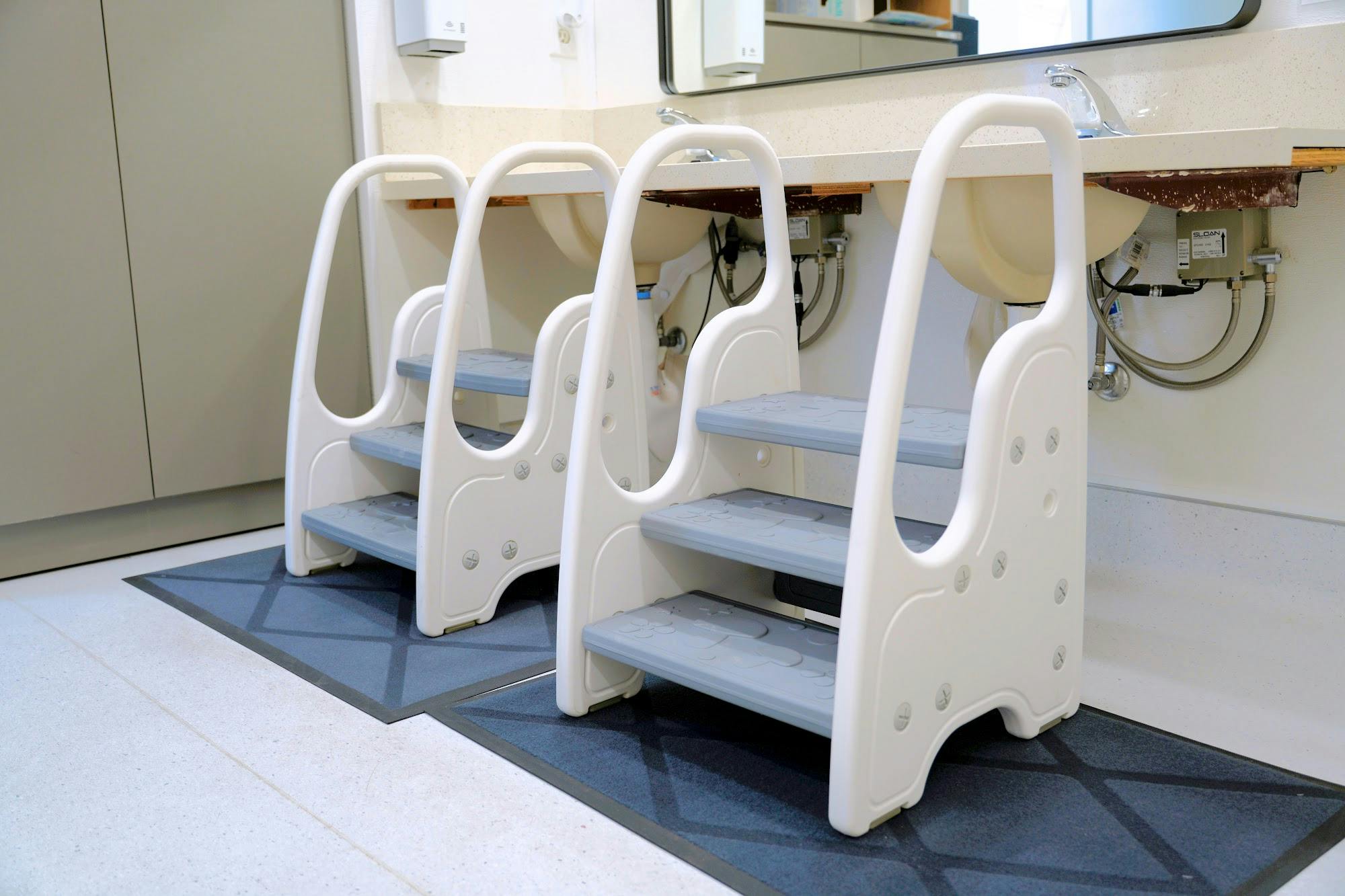 Two step stools positioned in front of a bathroom vanity