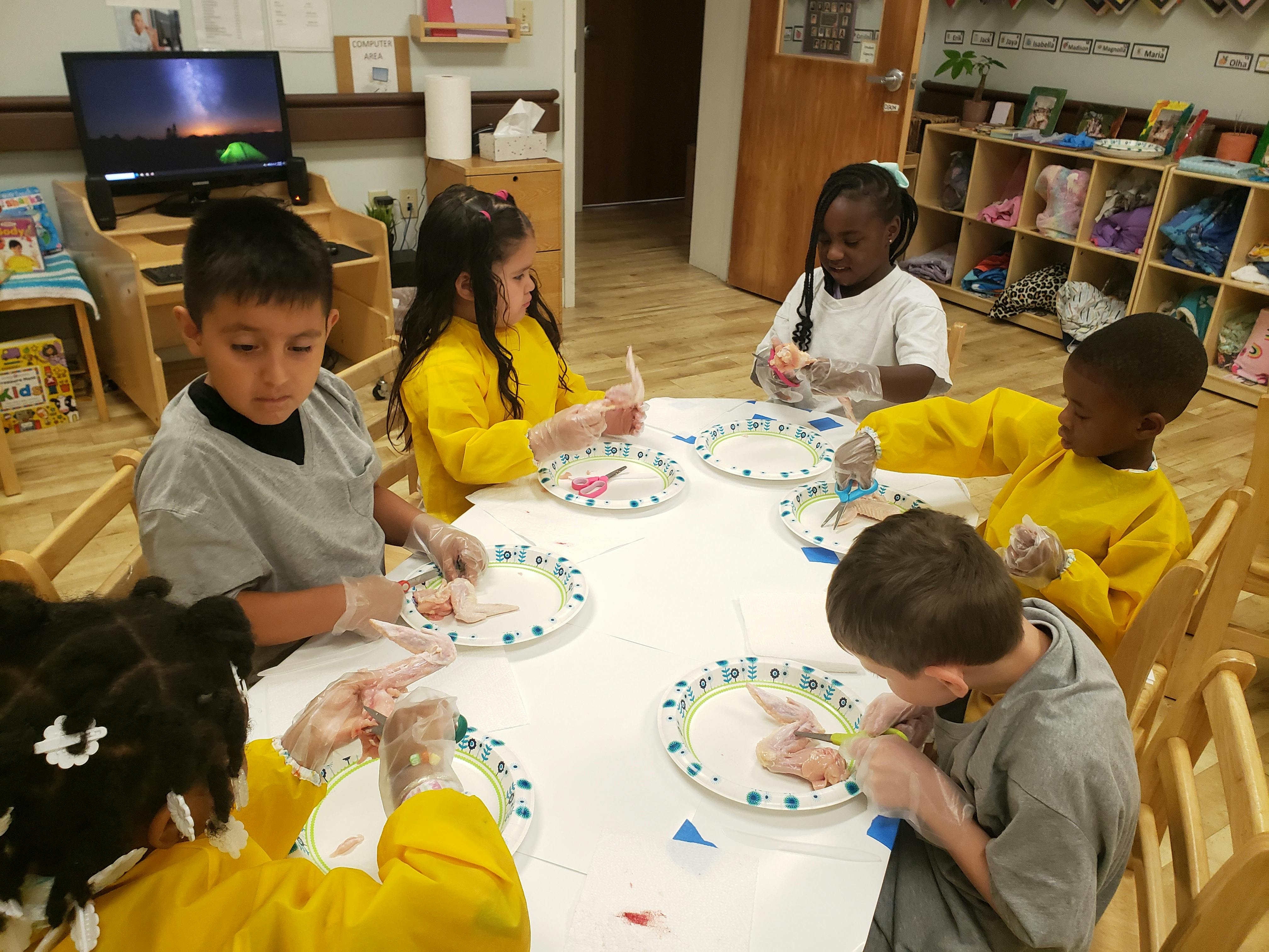Children wearing gloves and working on craft projects at a table