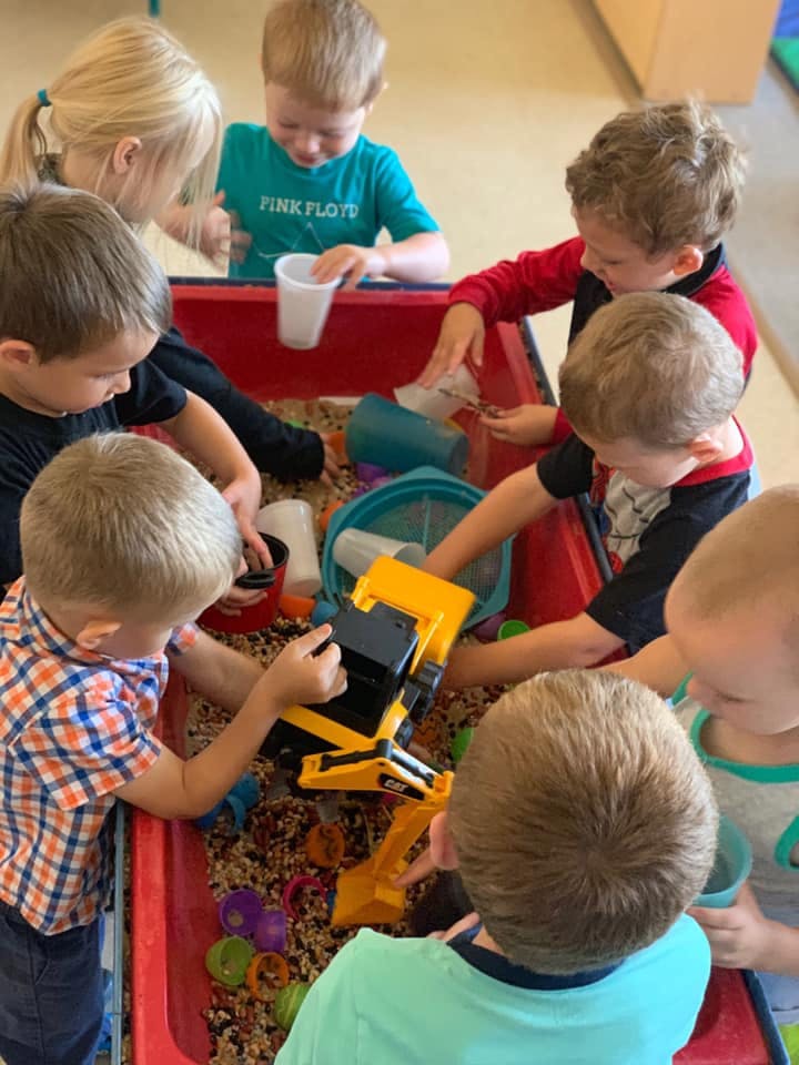 Children playing with toys in a sensory bin