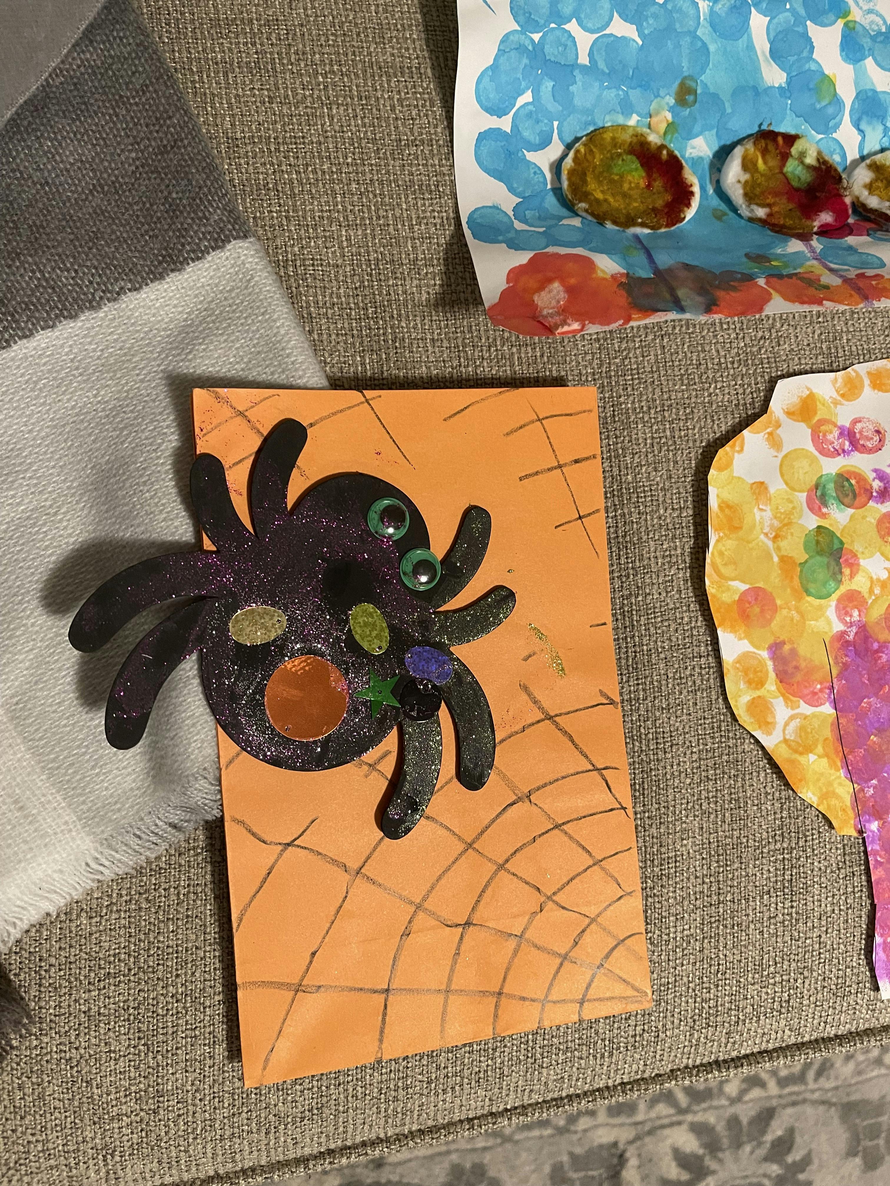 Child's craft project of a spider with googly eyes on orange paper