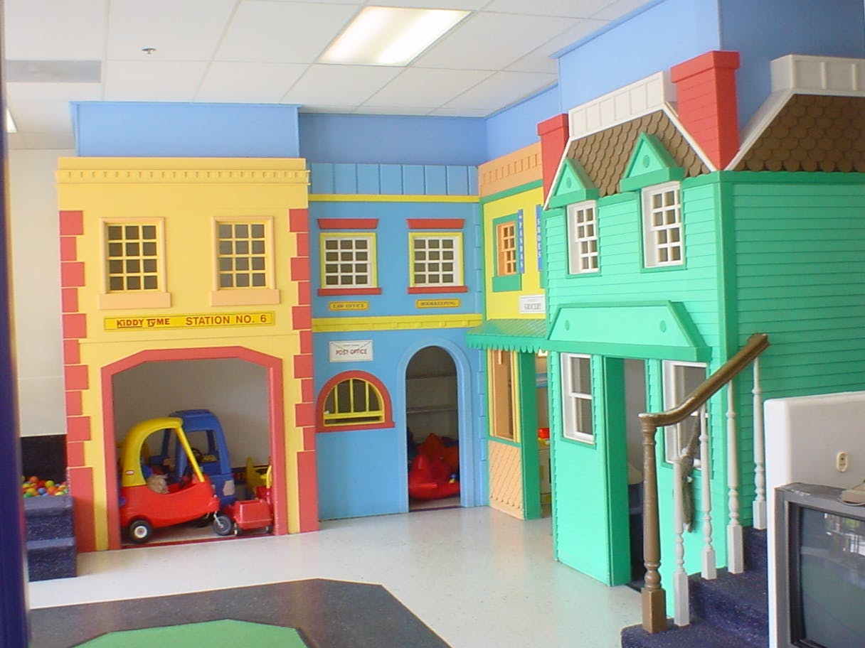 Indoor play area with colorful playhouses and toy cars