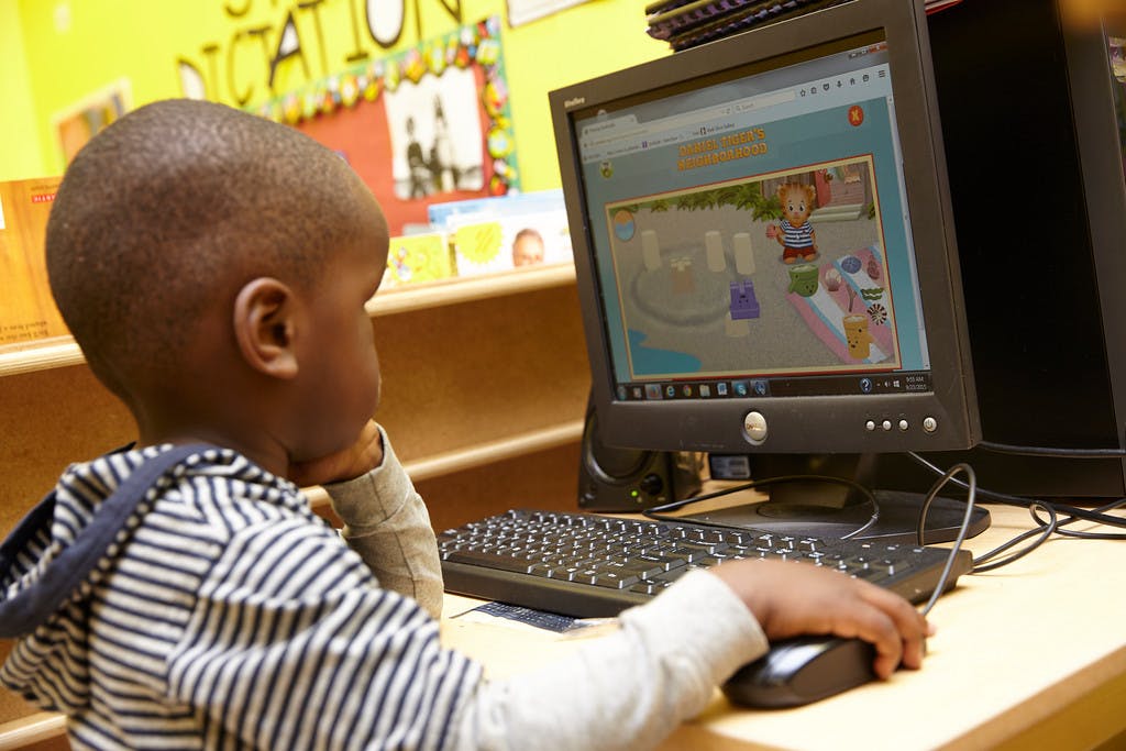 Child using a computer mouse in a classroom