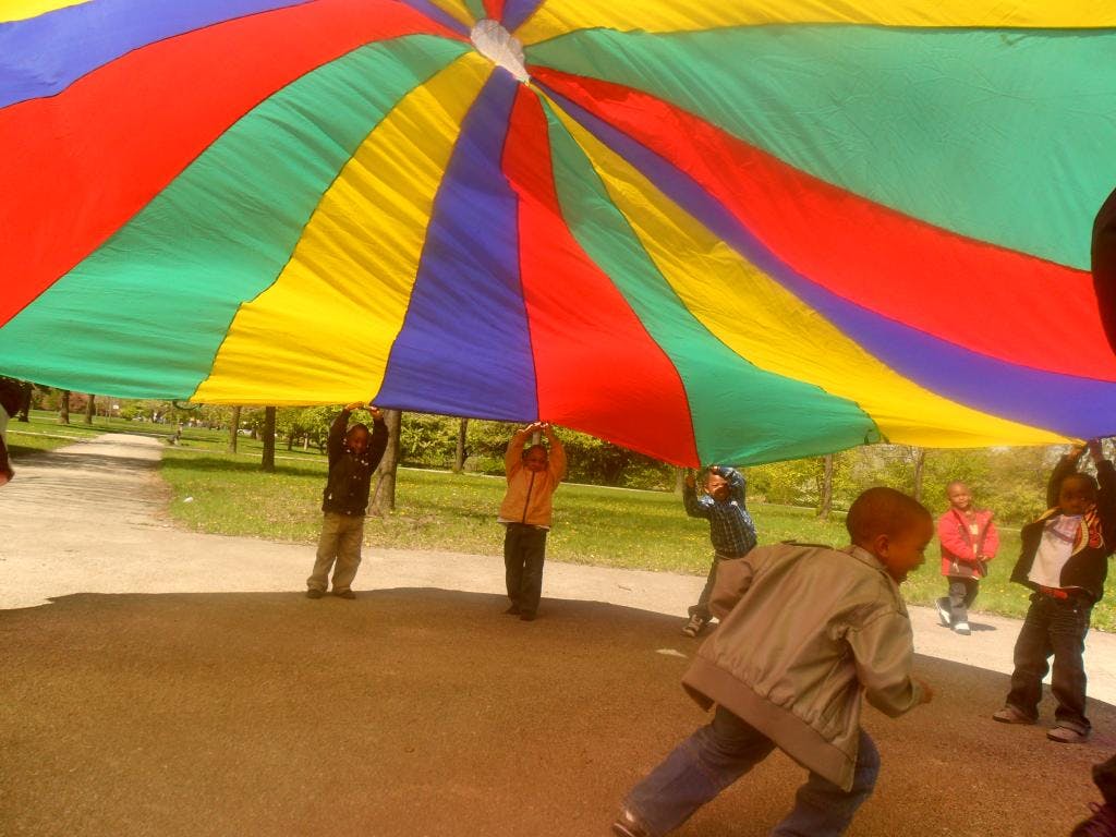 Children playing with a large colorful parachute
