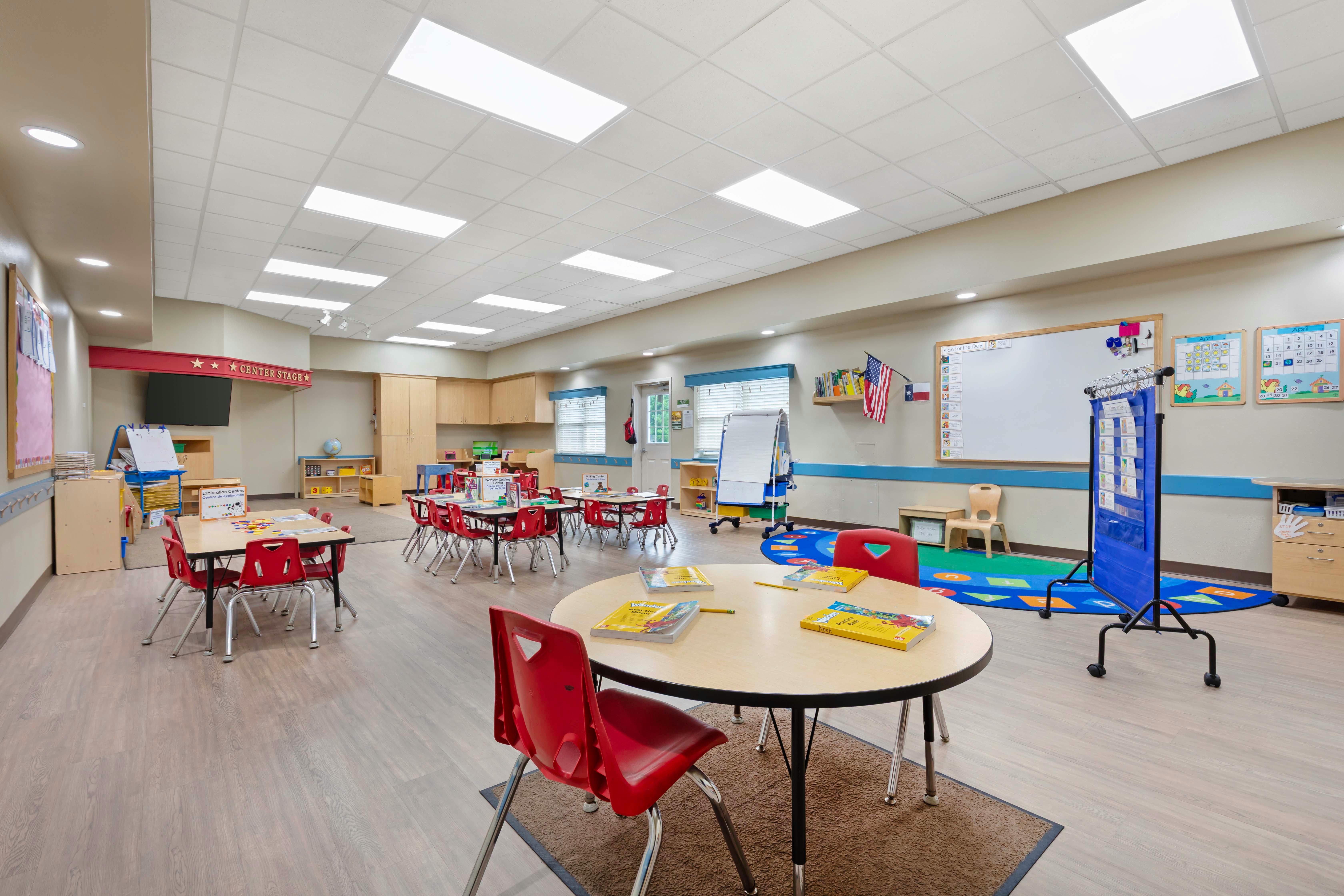 Classroom with tables, red chairs, and various learning stations