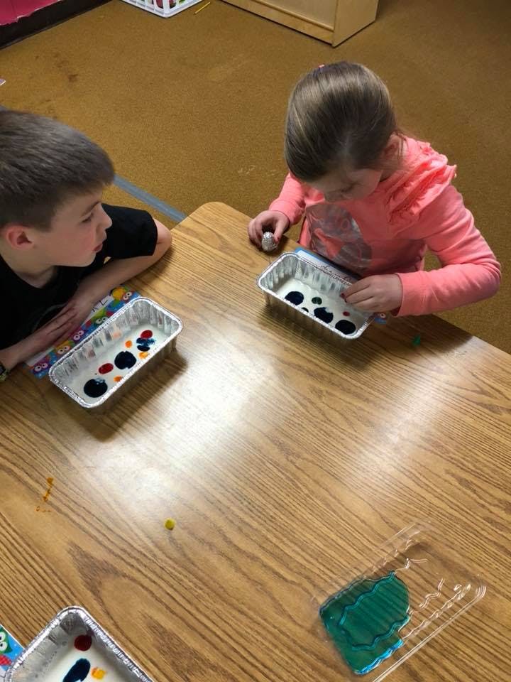 Two children at a table with trays of paint