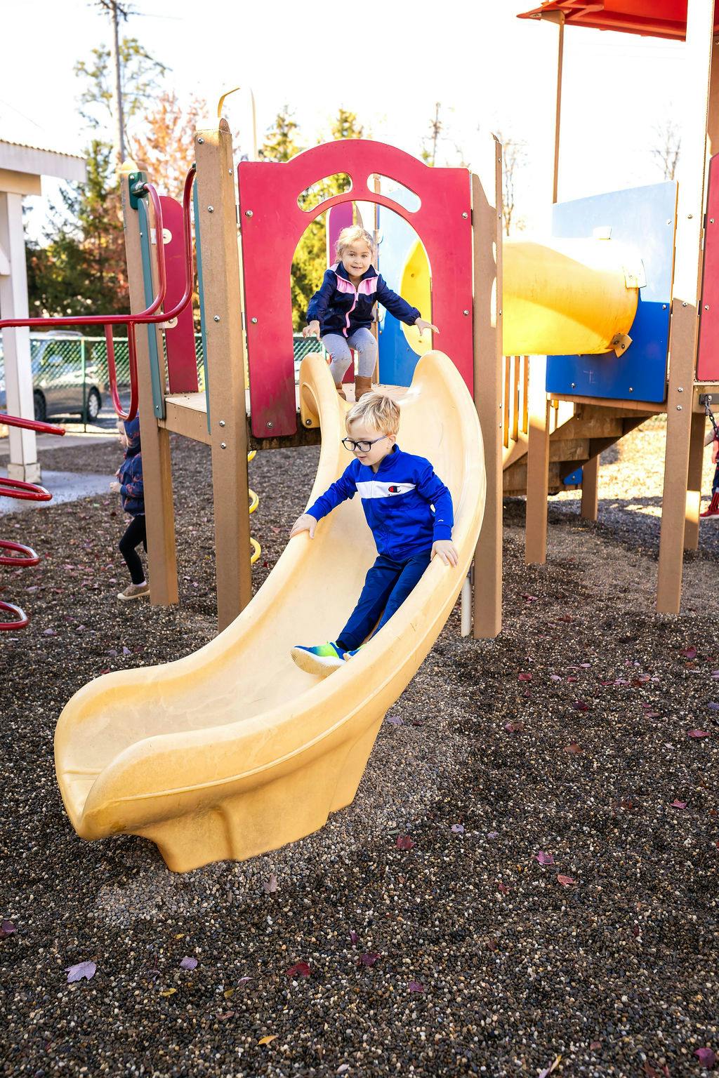 Child sliding down a yellow slide at a playground