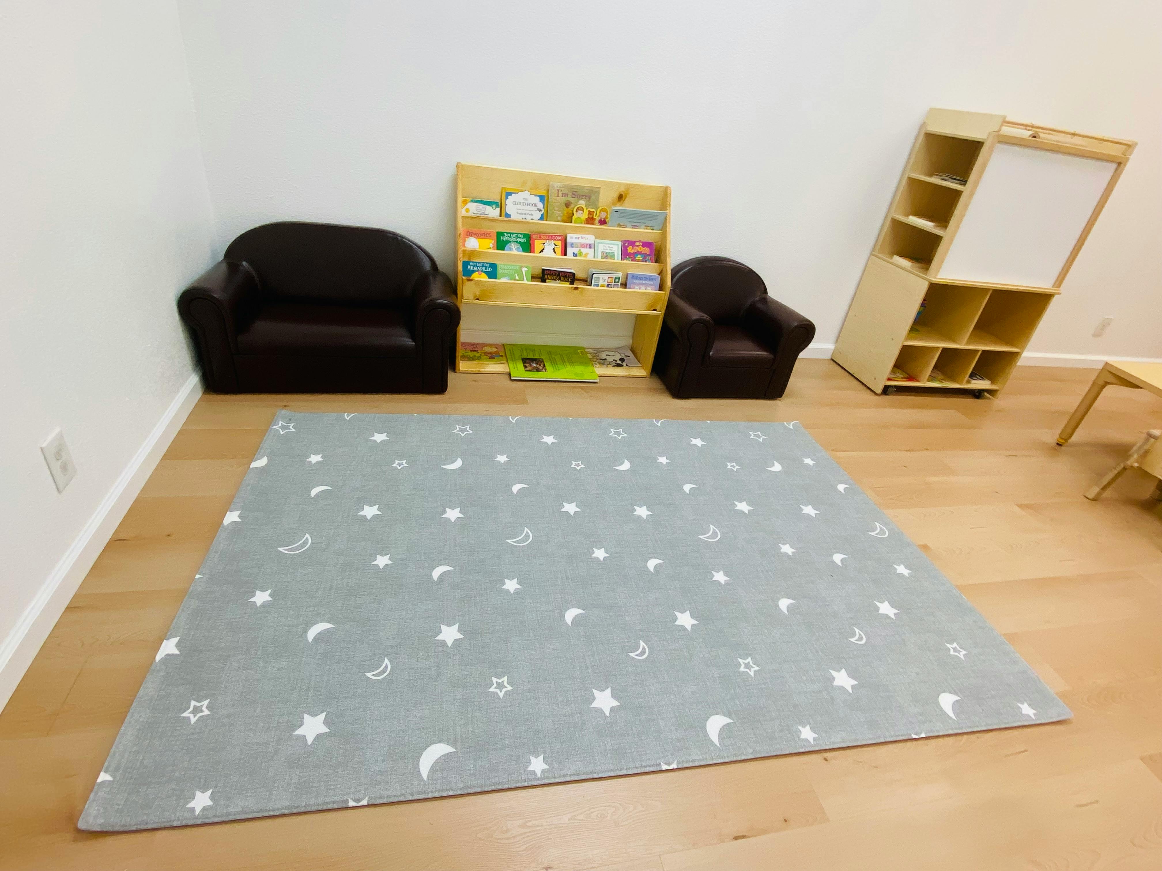 Playroom with a gray rug, two small chairs, and bookshelves