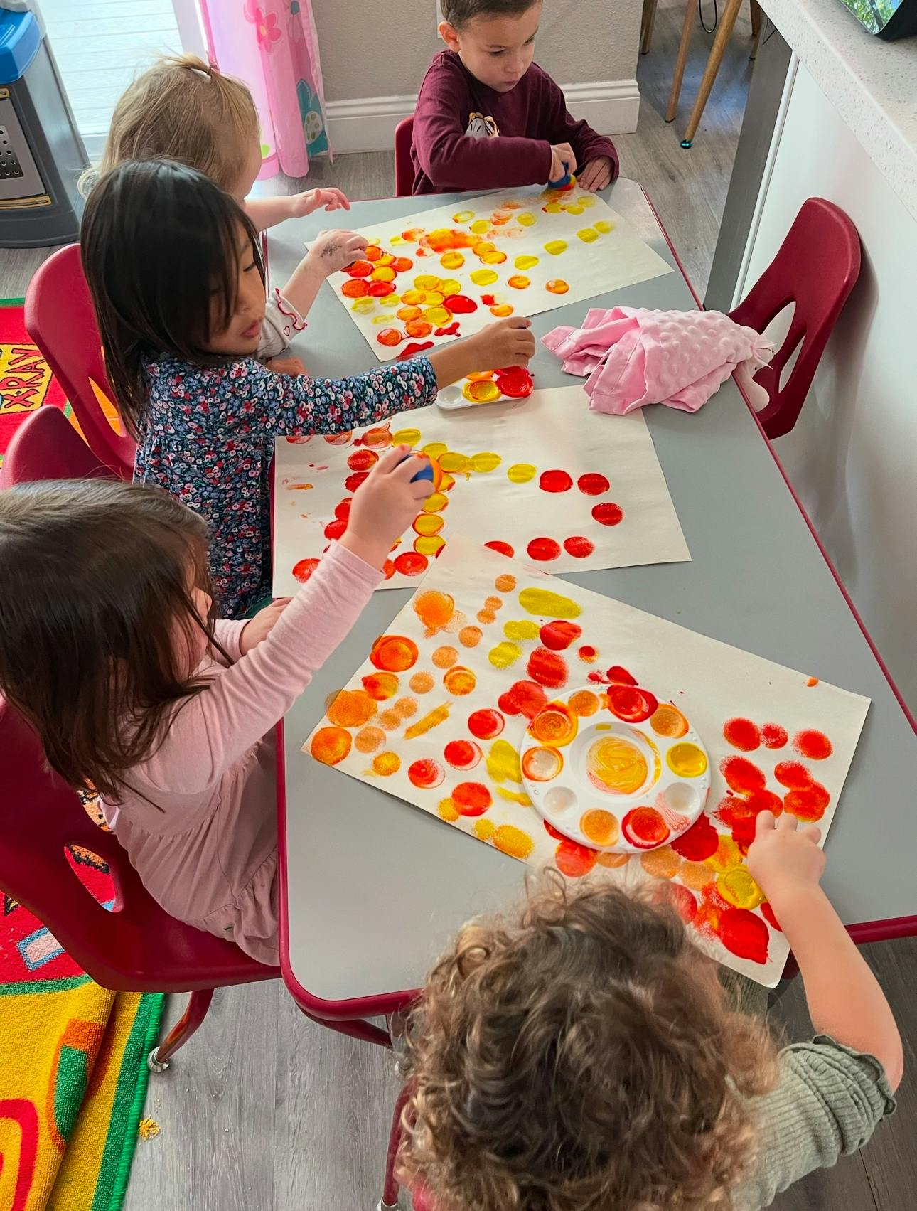 Children at a table doing a craft with colorful dots on paper