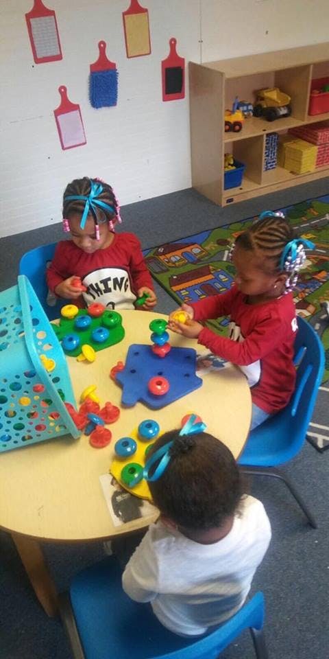 Three children playing with colorful stacking toys at a table