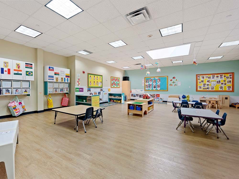 Empty classroom with small tables and chairs, flags, and colorful decorations
