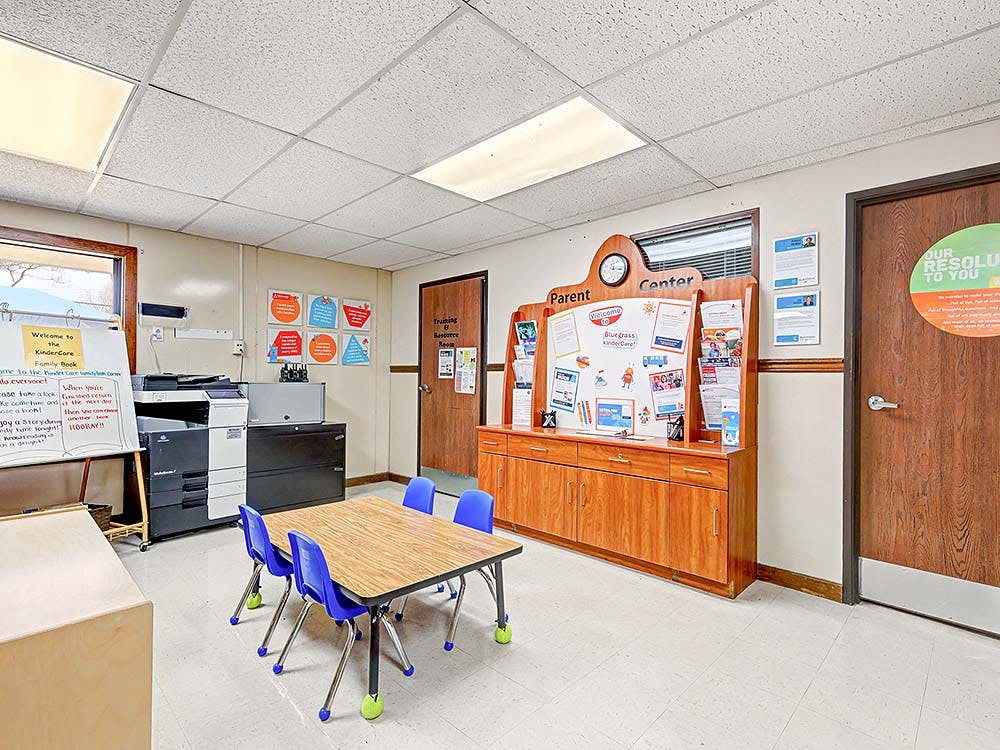 Classroom with child-sized table and chairs, printer, and parent information board