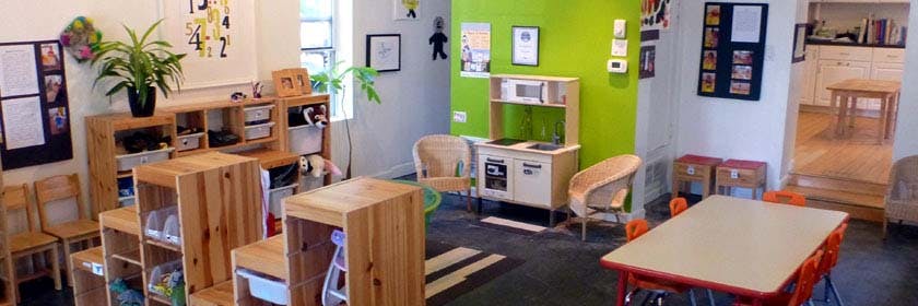 Classroom with small tables, chairs, and a play kitchen