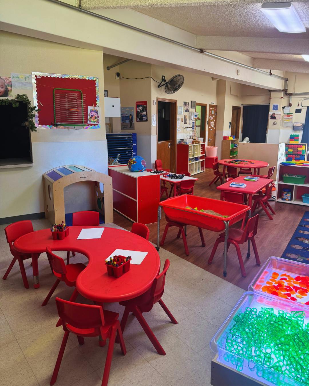 Empty classroom with small red tables and chairs