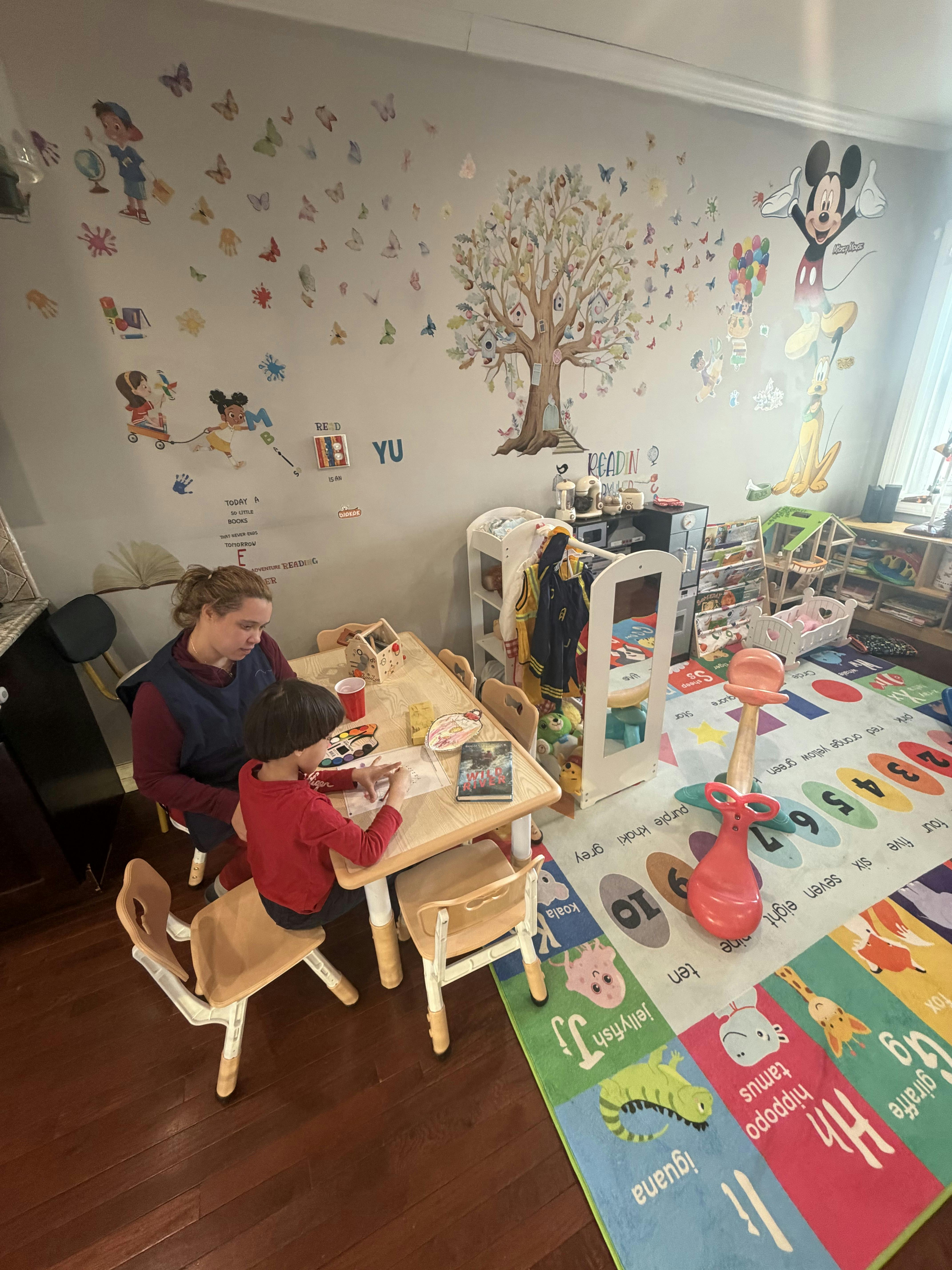 Adult and child coloring at a table in a classroom