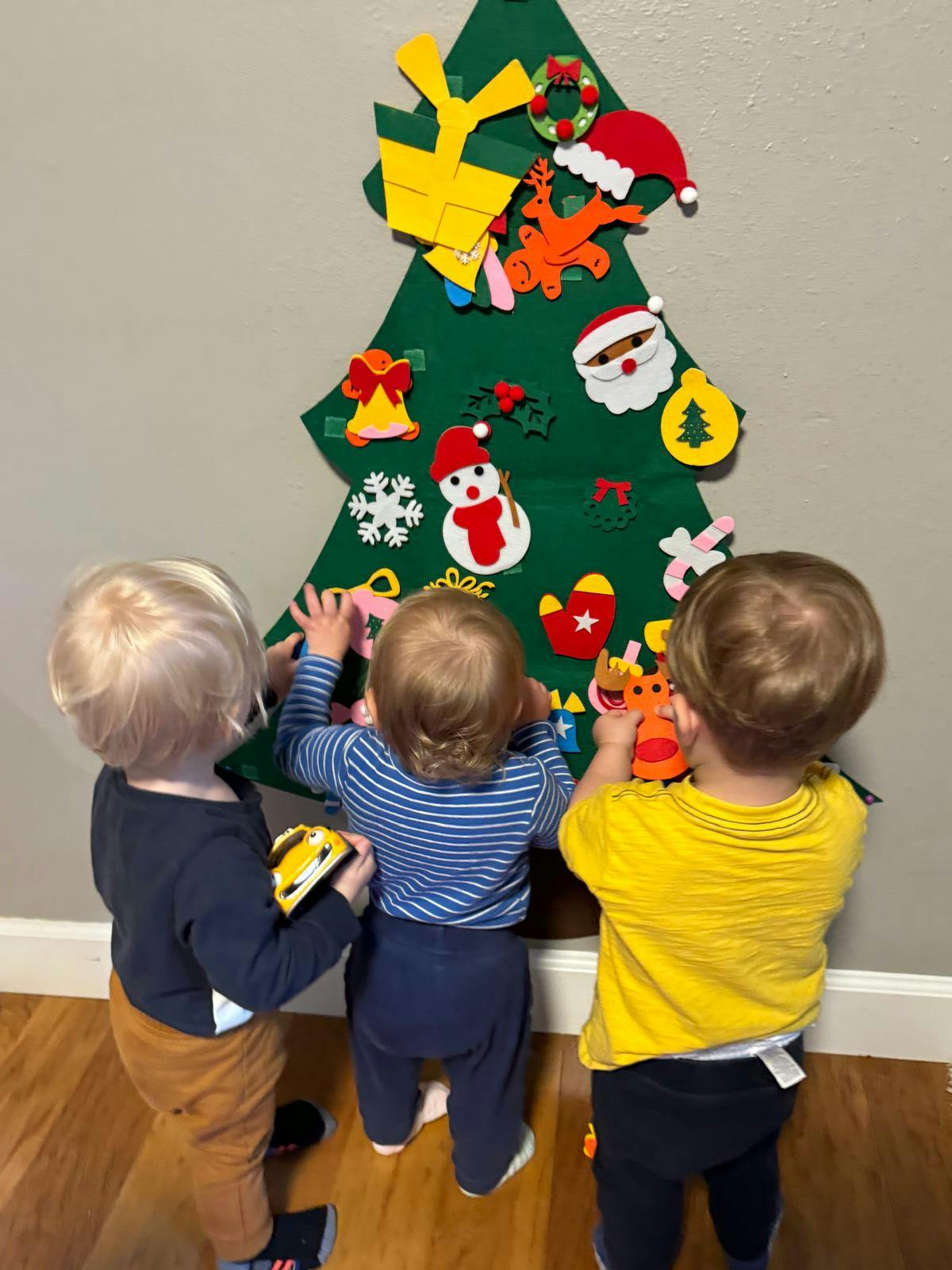 Three children playing with a felt Christmas tree