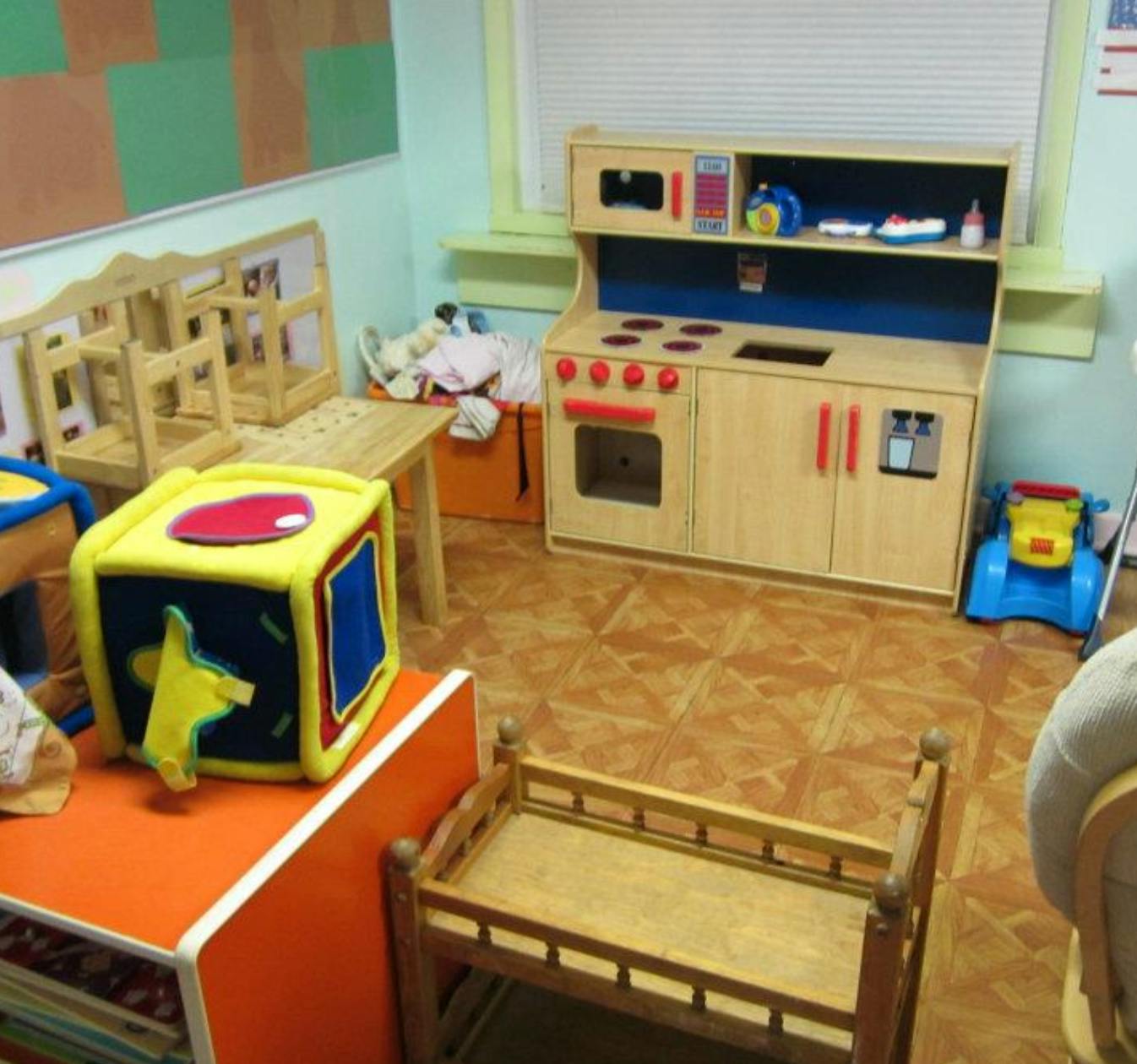 Playroom with toy kitchen, wooden crib, and soft block