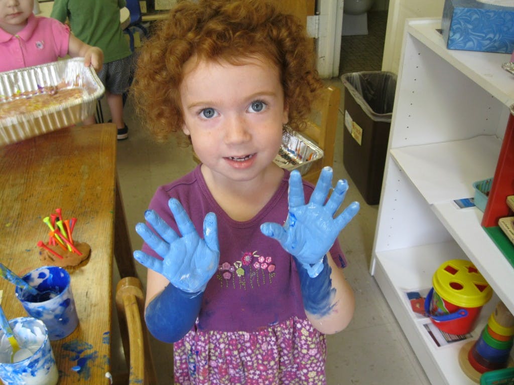 Child with blue paint on hands and forearms