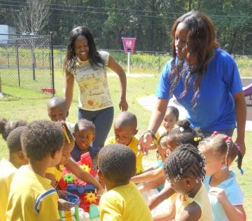 Two adults with a group of children playing outdoors