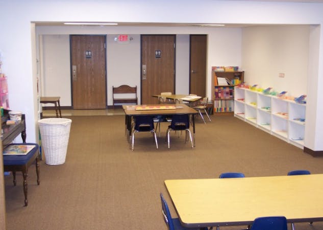 Classroom with tables, chairs, shelves, and closed doors