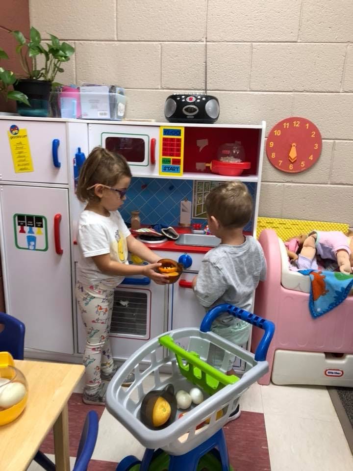 Two children playing with a toy kitchen set