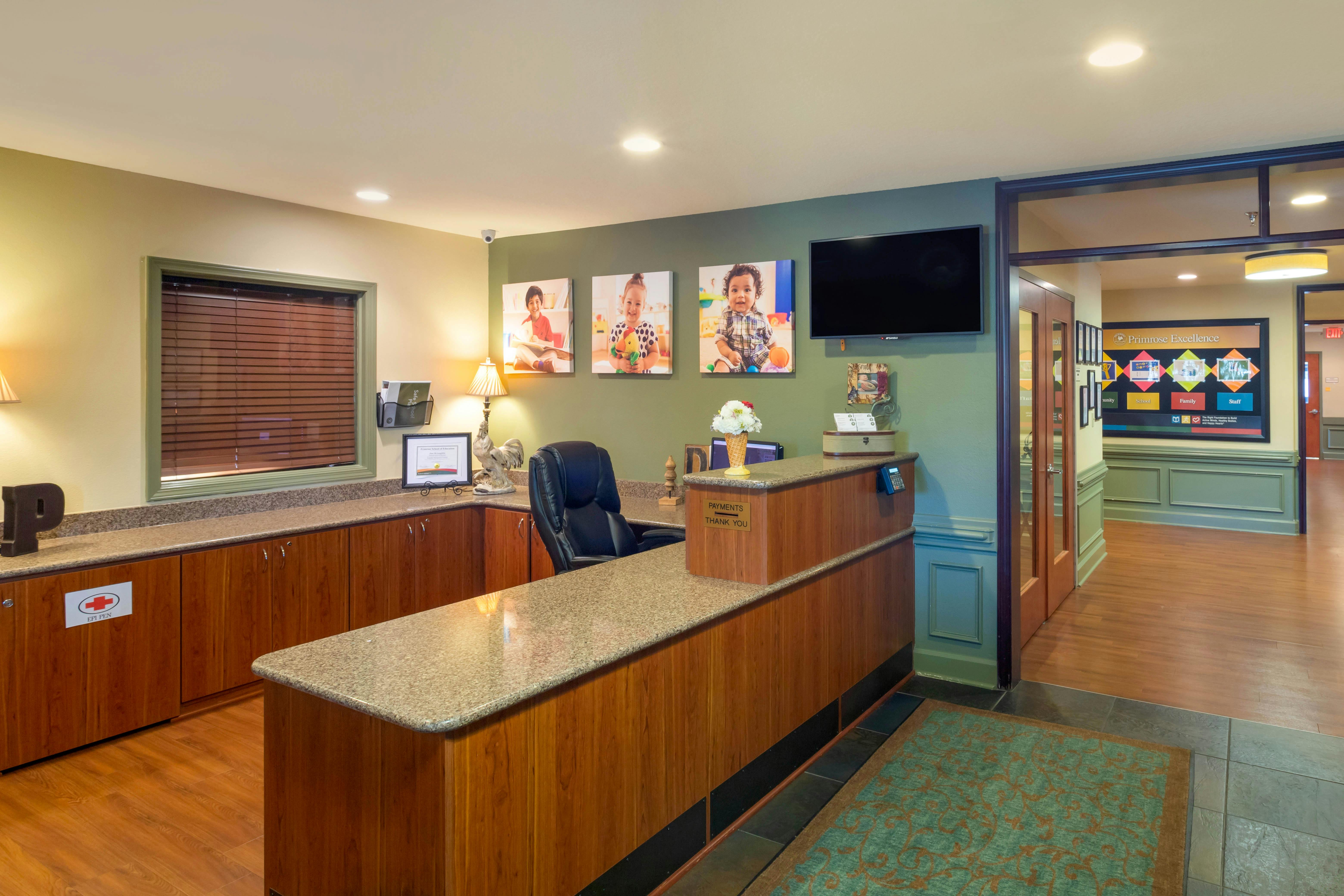 Reception desk with office chair, monitor, and images of children on the wall