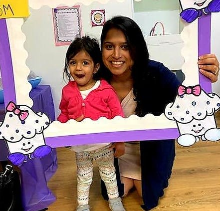 Person and child posing in a cupcake-themed photo frame