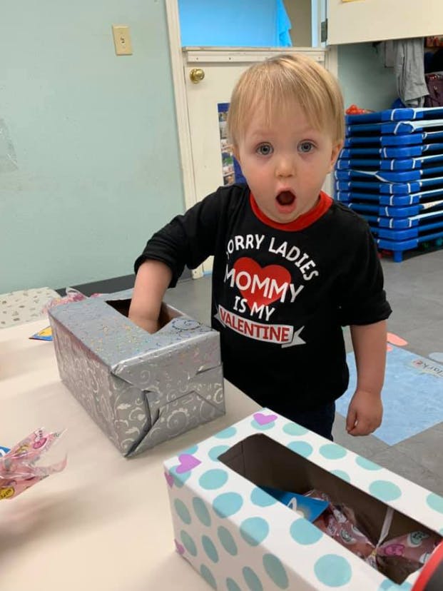 Child with hand in a box, wearing a shirt that says "Mommy is my Valentine"