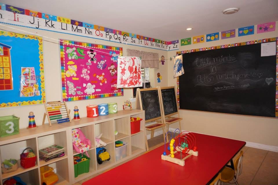 Classroom with a red table, shelves of toys, and a blackboard