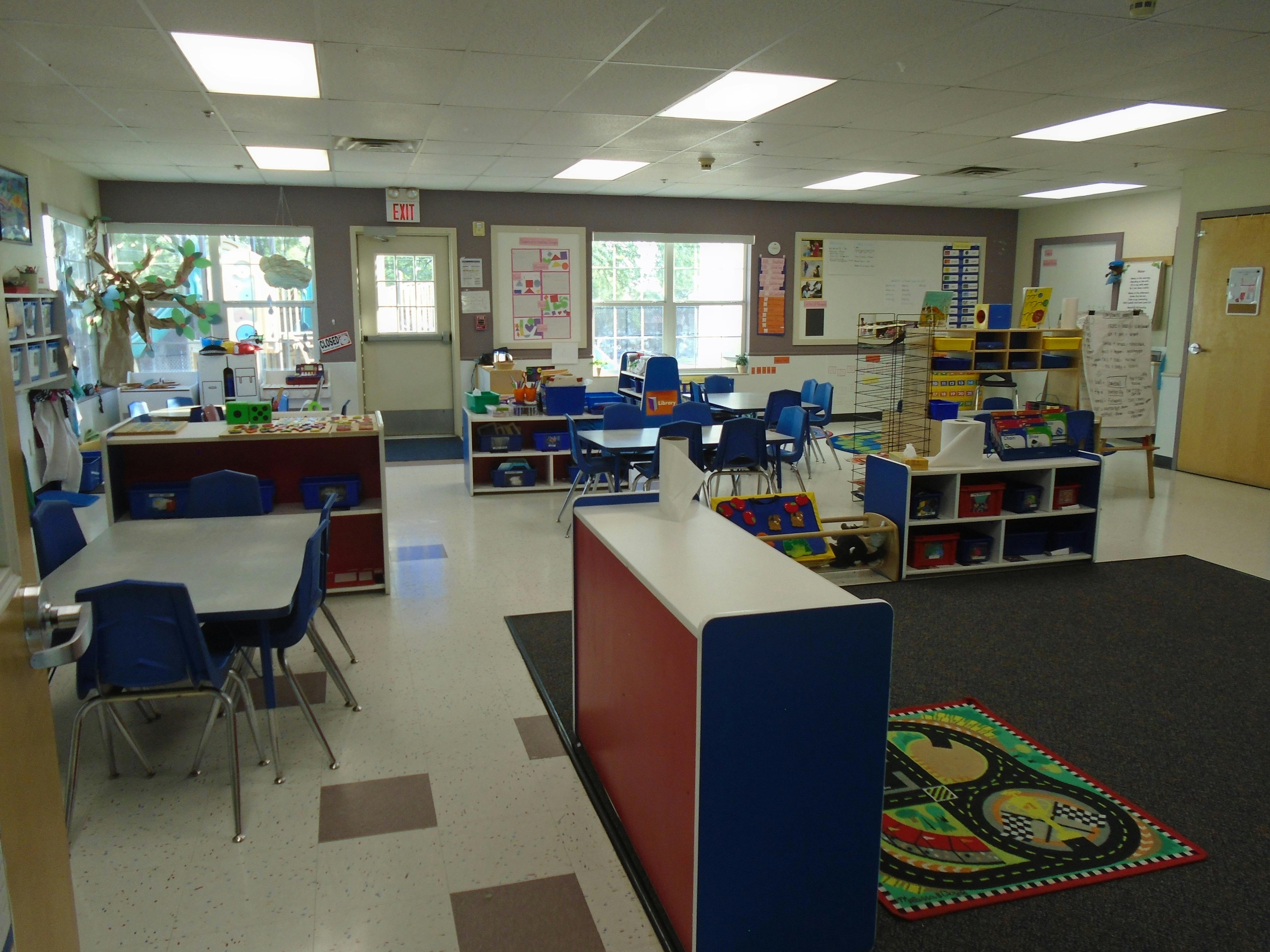 Empty classroom with small blue chairs, tables, and learning materials