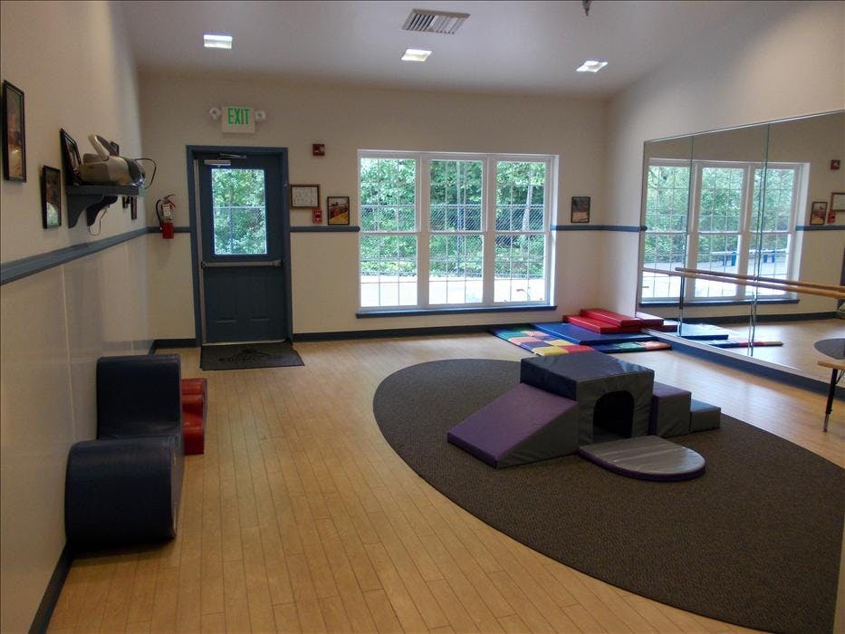 An empty indoor play area with padded blocks, mats, and a mirror