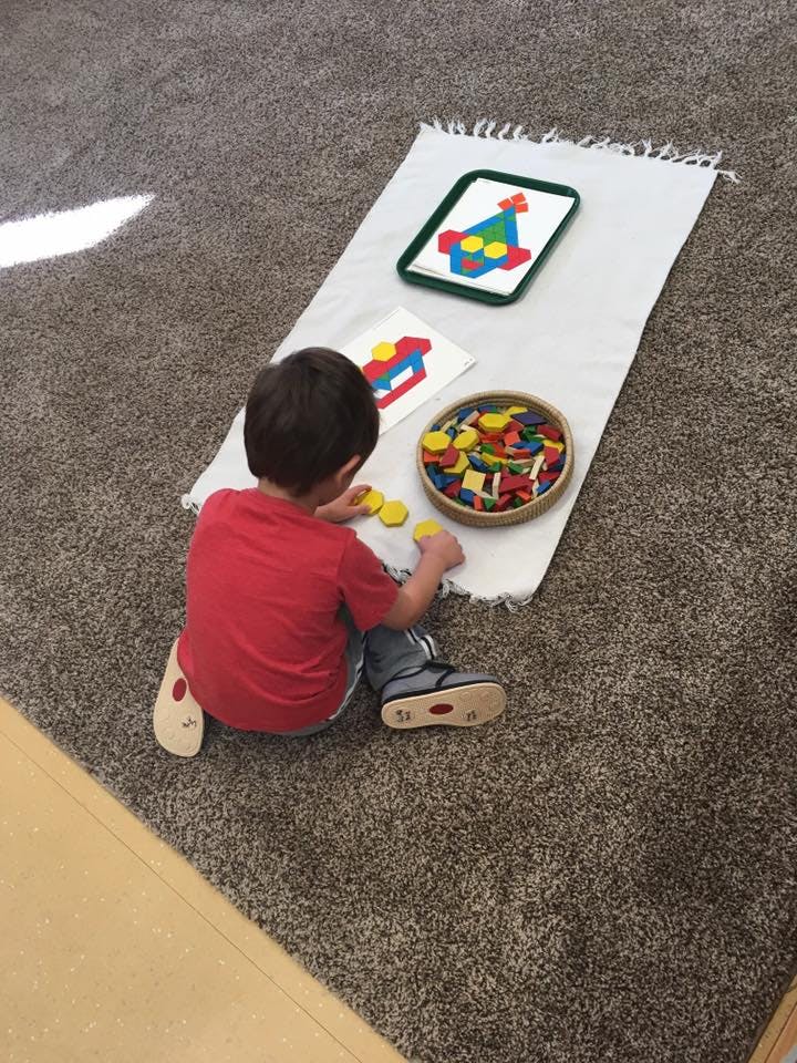 Child playing with colorful geometric shapes on a white mat