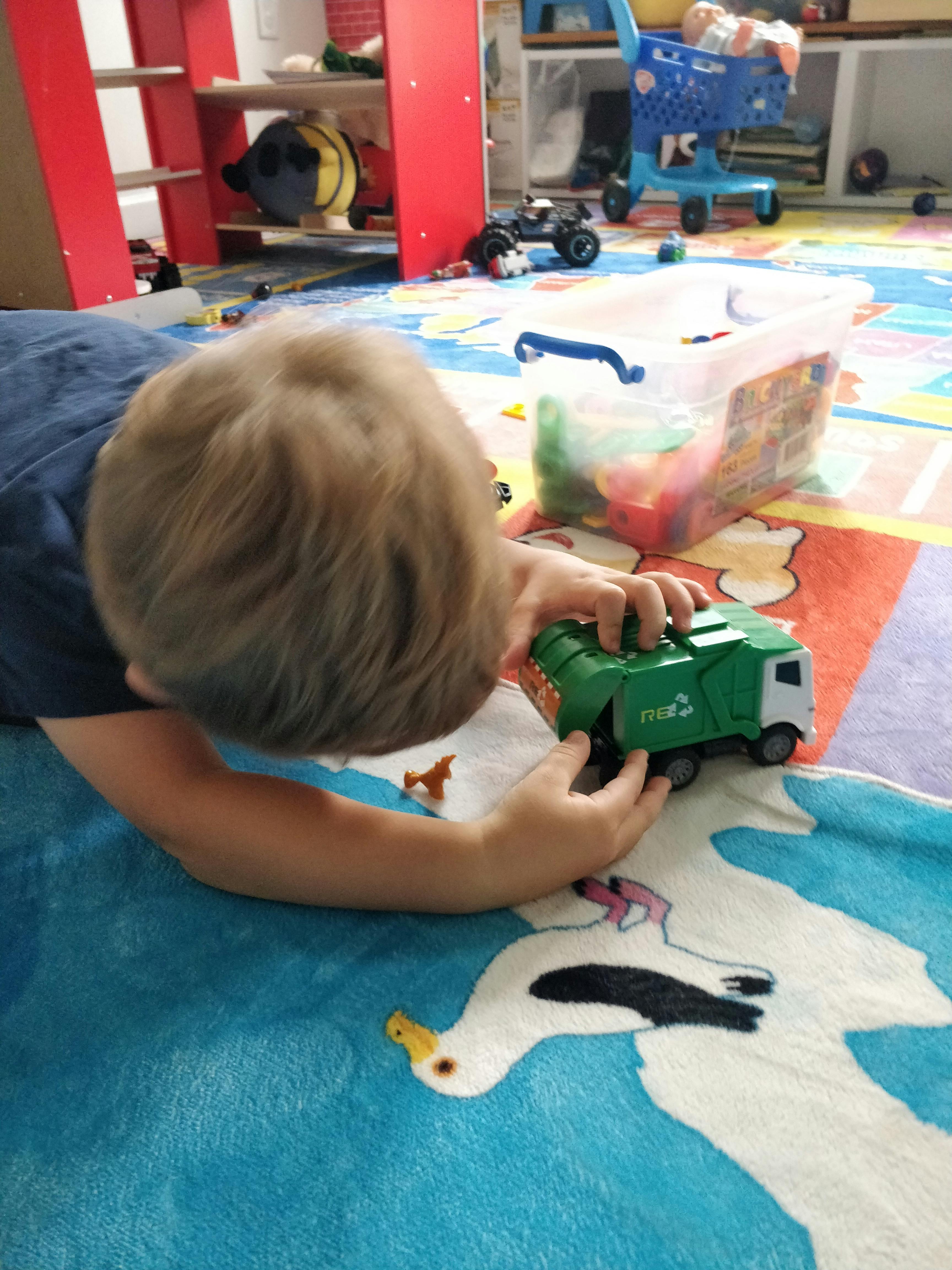 Child playing with a toy garbage truck on a play mat