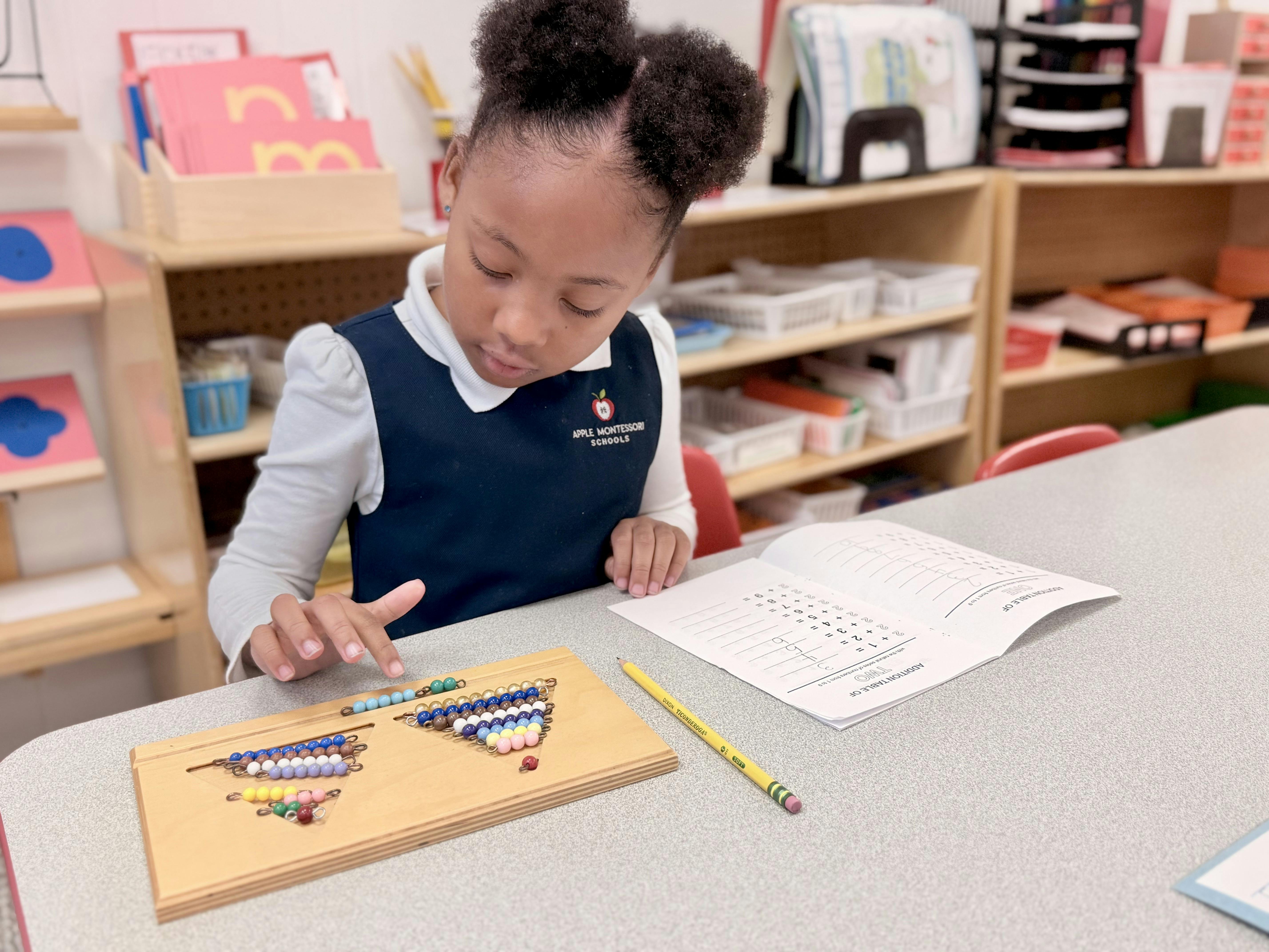 Child learning math using a counting bead board and an 'Addition Table' worksheet