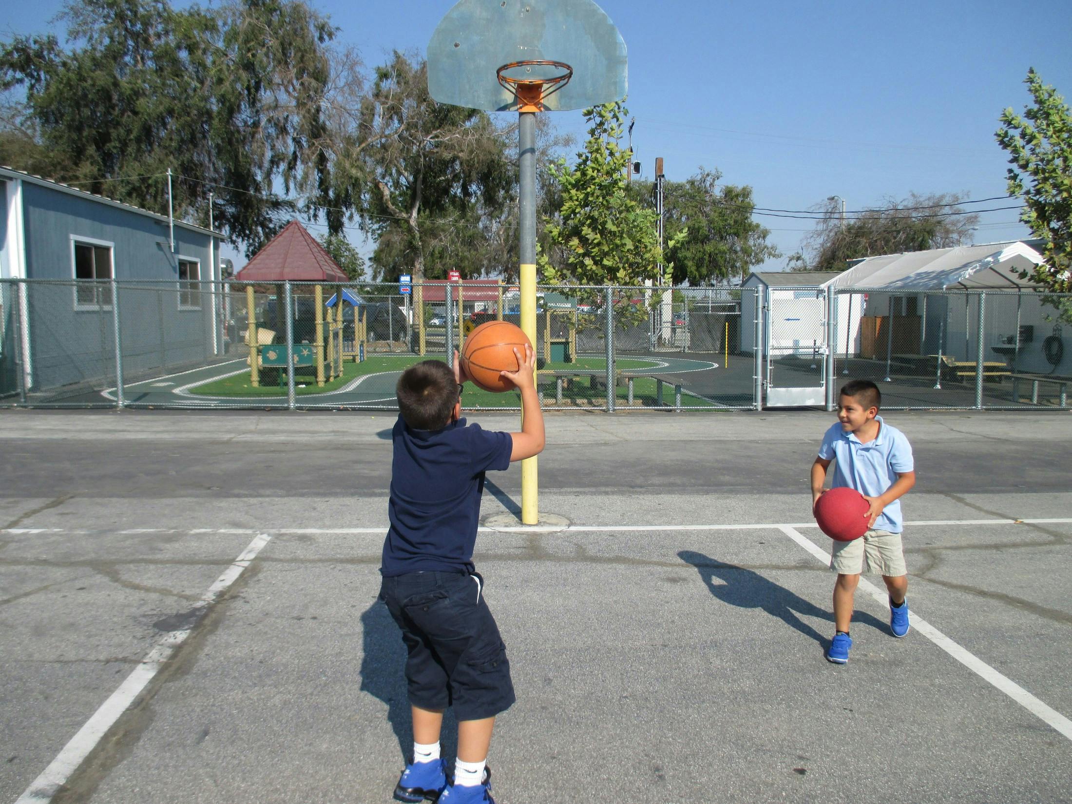Two children playing basketball on a court