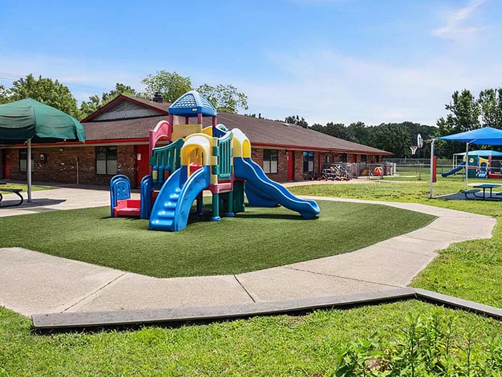 Colorful playground set on artificial turf with a building in the background