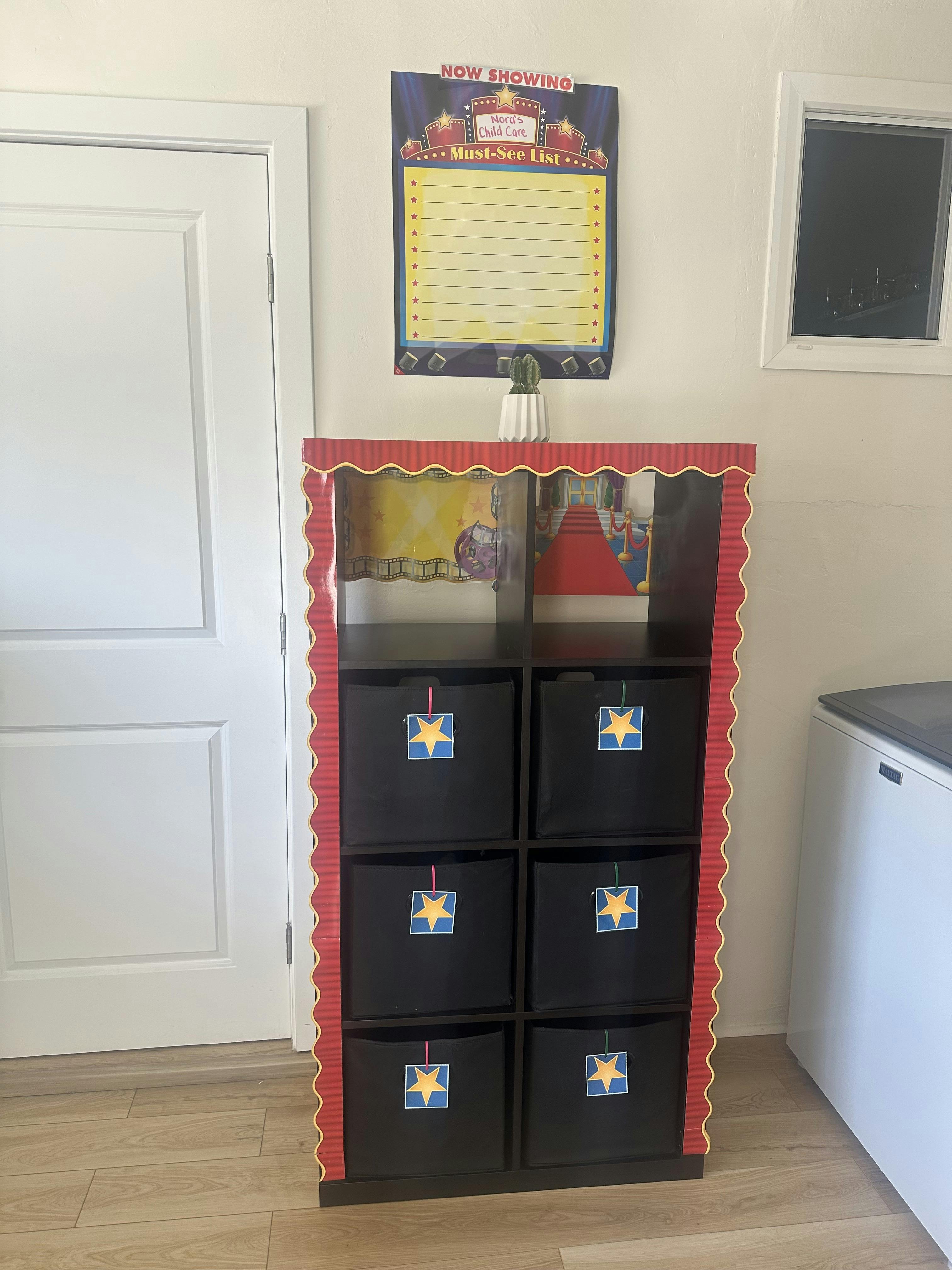 movie-themed shelving unit with black bins, a checklist, and a cactus