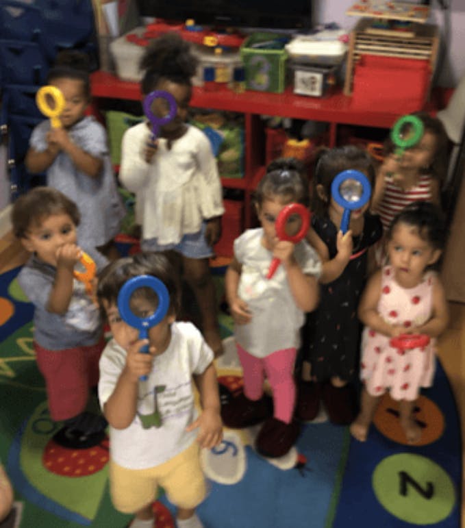 Children holding up colorful magnifying glasses in a classroom