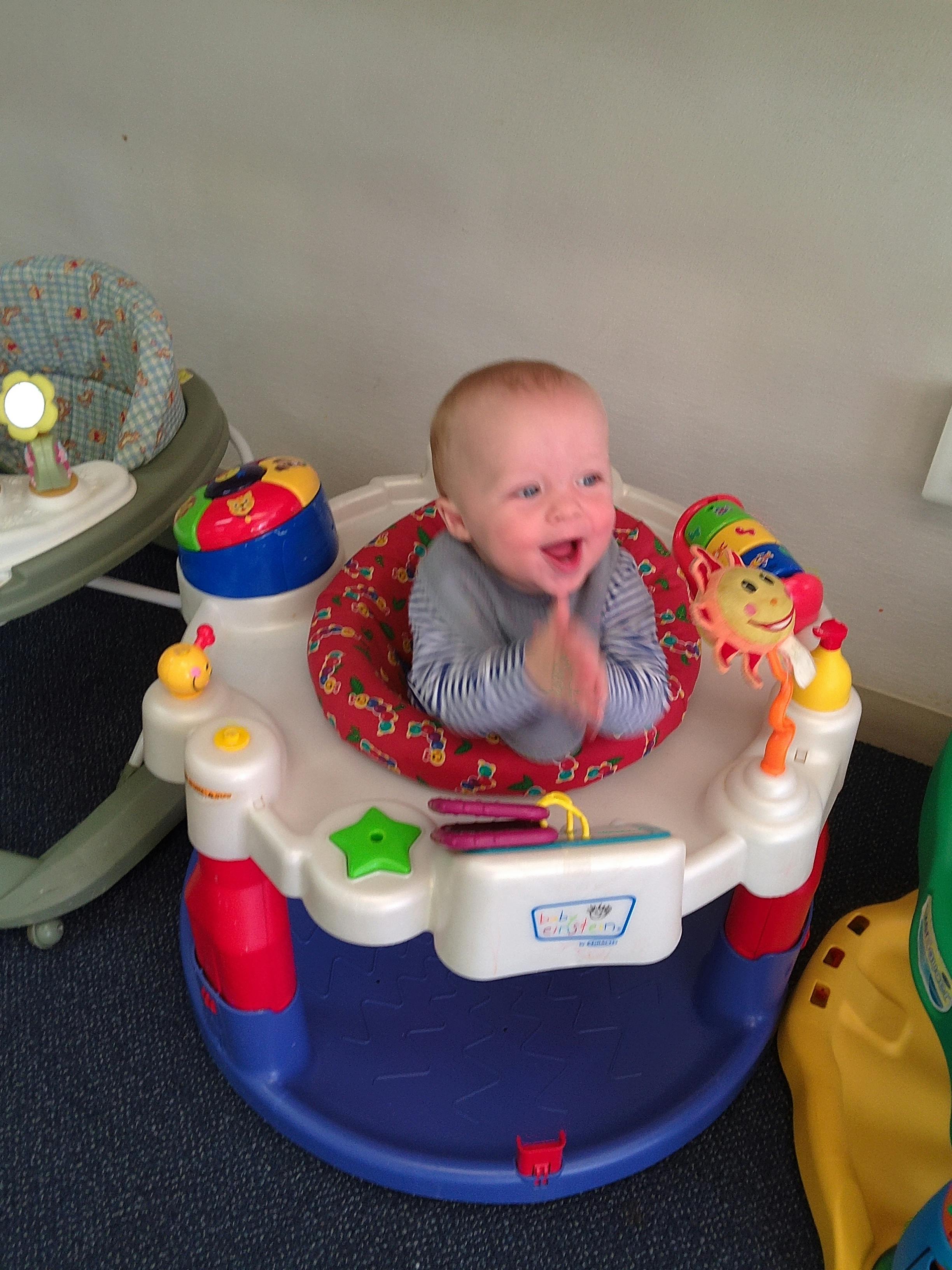 Child in a baby activity center clapping hands