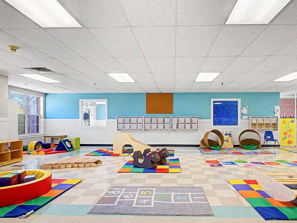 Childcare classroom with soft play equipment and colorful rugs