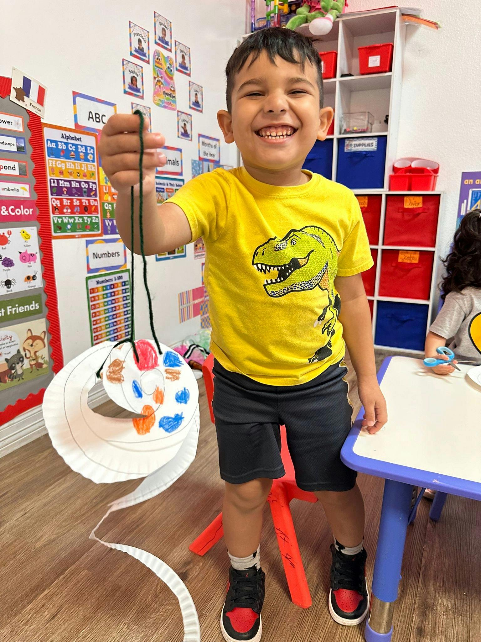 Child holding up a paper craft in a classroom