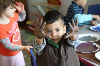 Child with paint on hands in a classroom