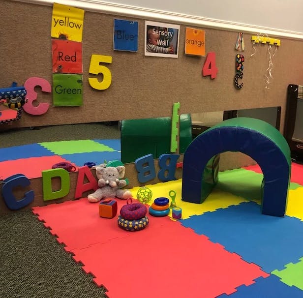 Playroom with colorful floor mats, soft play equipment, and large letters