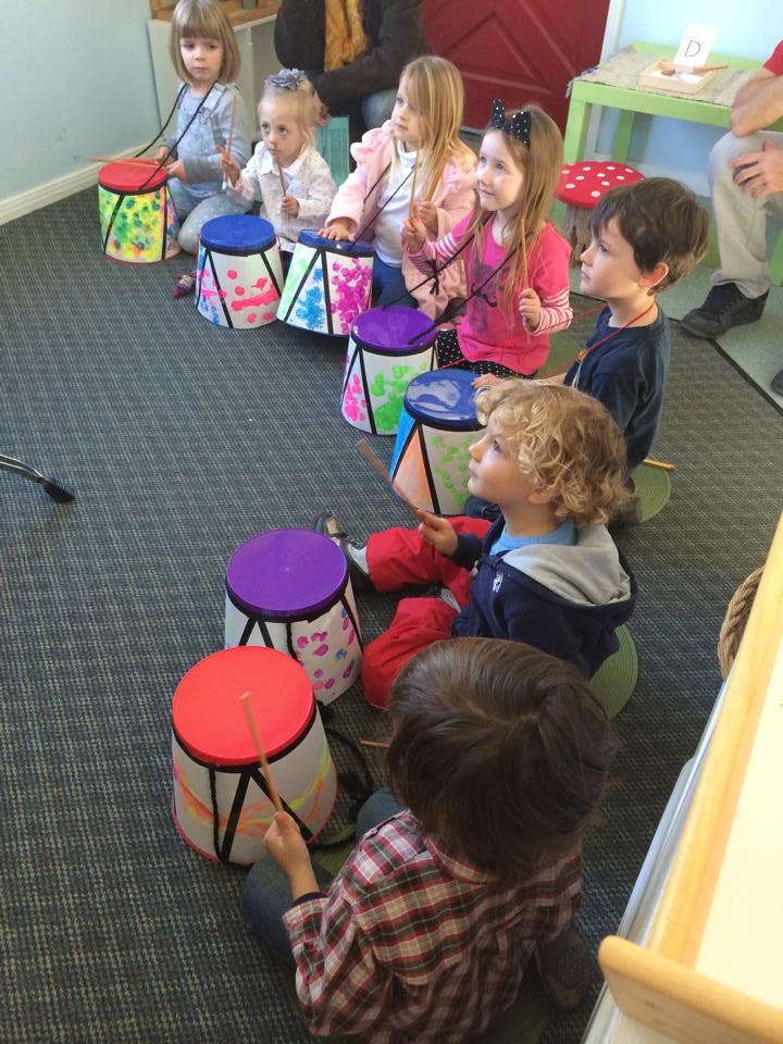 Children sitting on the floor playing drums