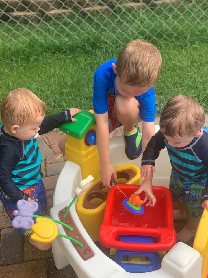 Three children playing with a water table outdoors